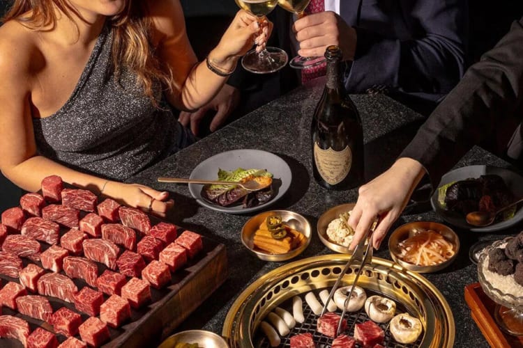 Close-up shot of people enjoying a steak meal with a variety of sides at Cote Korean Steakhouse