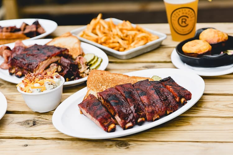 Ribs and toast in the foreground with other meals in the background from County Road Ice House