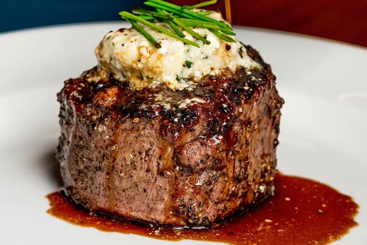 Close-up of a steak topped with mashed potato and herbs from Cowford Chophouse