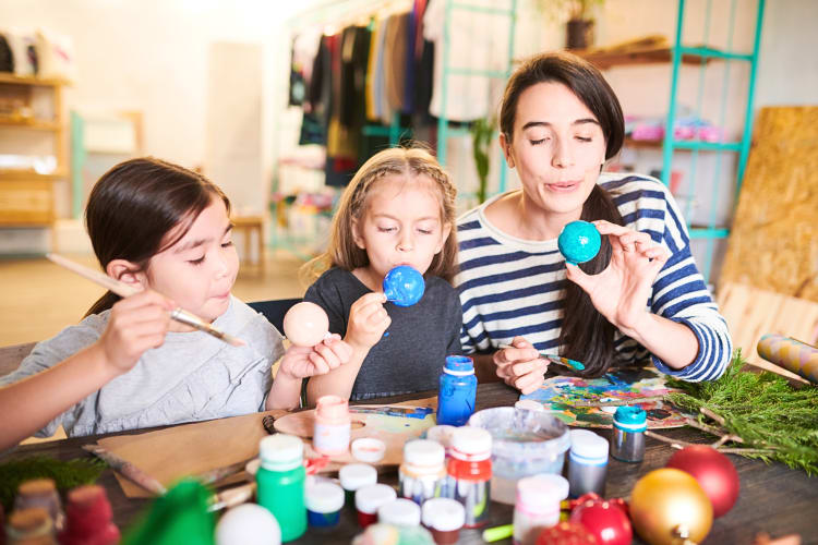 A mother and her two daughters making Christmas ornaments together