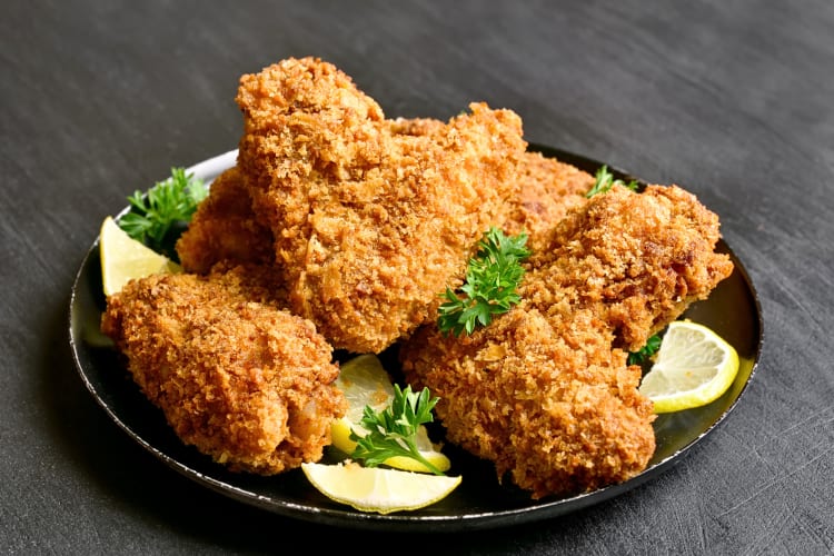 Crispy chicken pieces on a plate with garnish and lemon slices