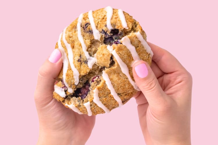 A person splitting open a blueberry crumb cake cookie