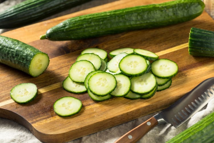 Whole cucumber and sliced cucumber on a wooden board