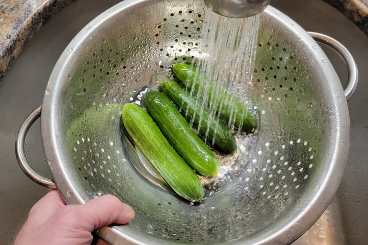 A person washing cucumbers