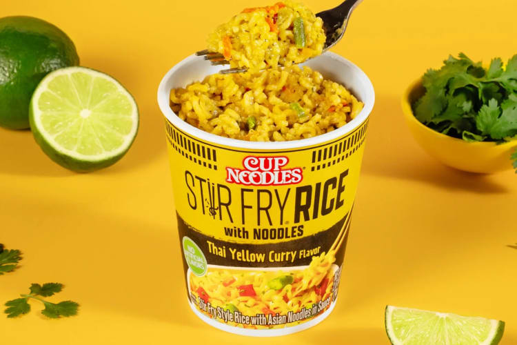 A Stir-Fry With Rice Noodles Yellow Curry Cup Noodle next to fresh lime and cliantro