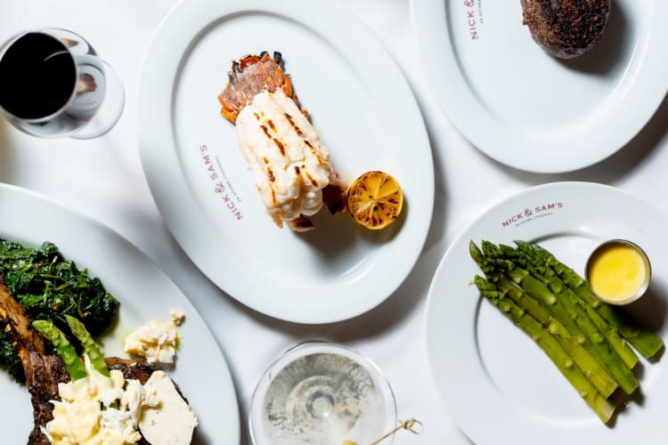 Lobster, steak and asparagus dishes on a table