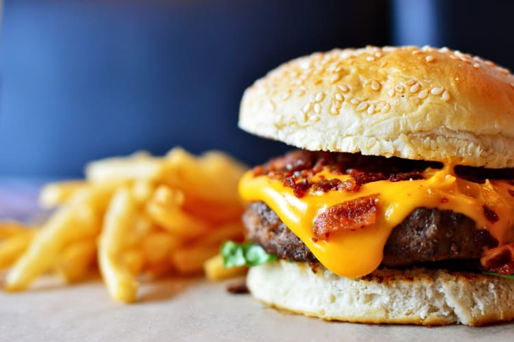 Bacon and cheese burger with fries in the background