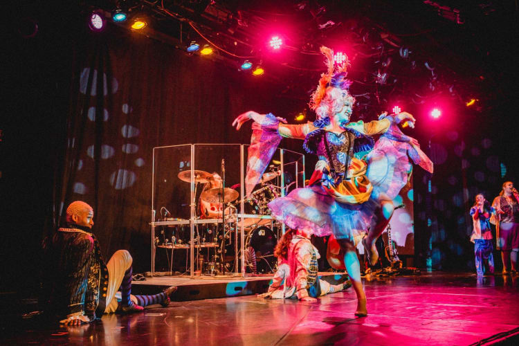 An artist performinng on stage in a colorful costume