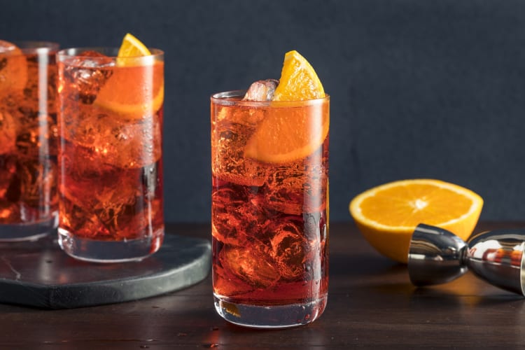 Orange cocktails next to a slice of orange