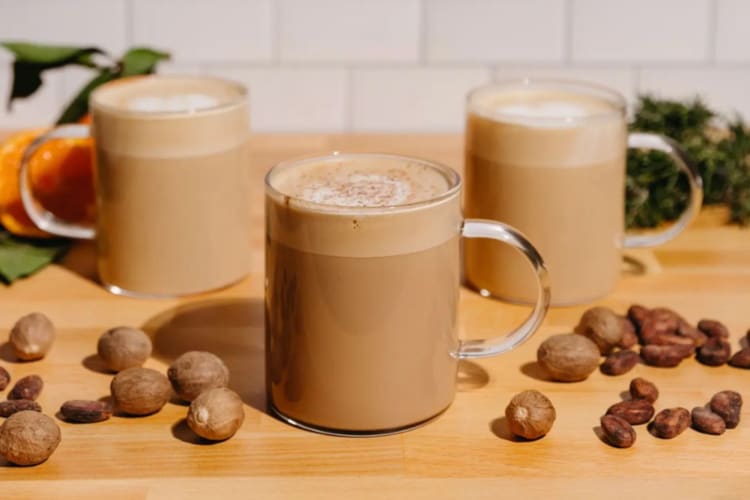 Cups of coffee next to coffee beans