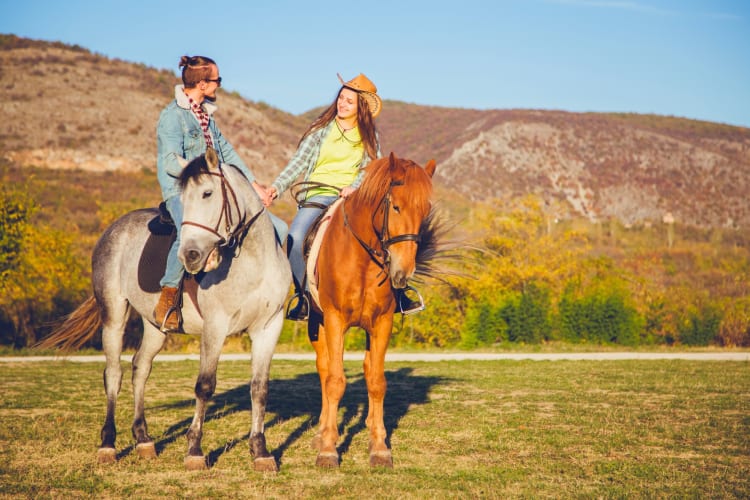 A couple on horseback next to mountains