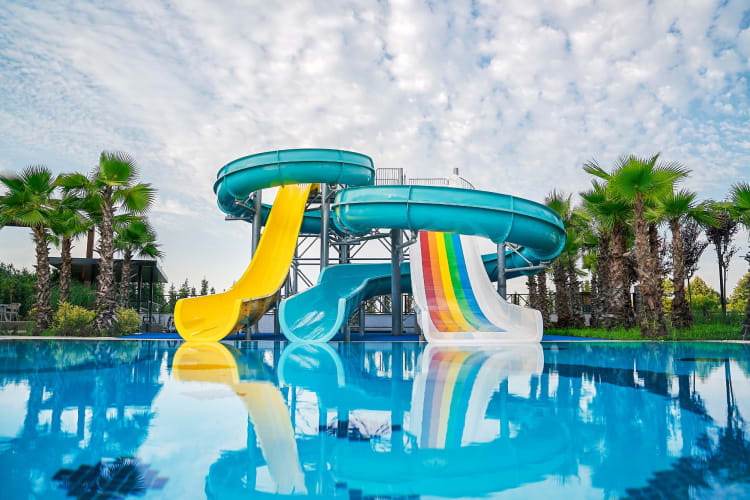 Colorful waterslides by a pool and palm trees