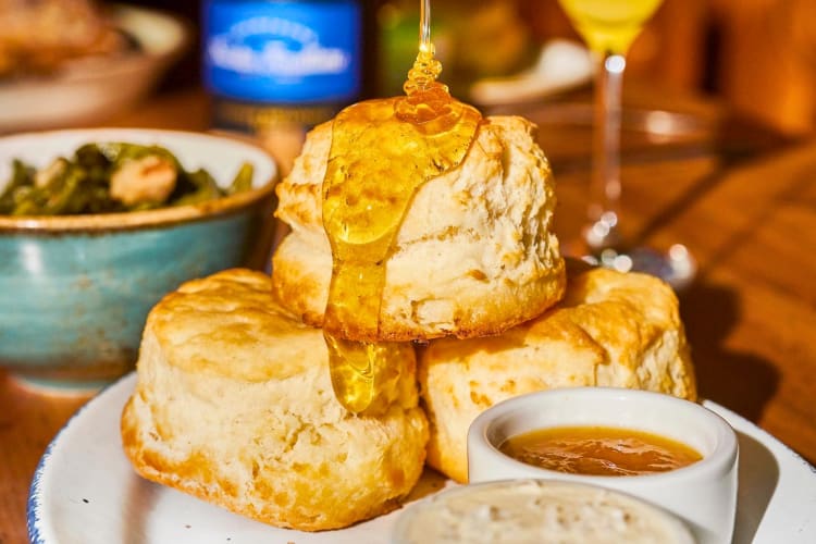 Three biscuits stacked up with honey drizzled over them