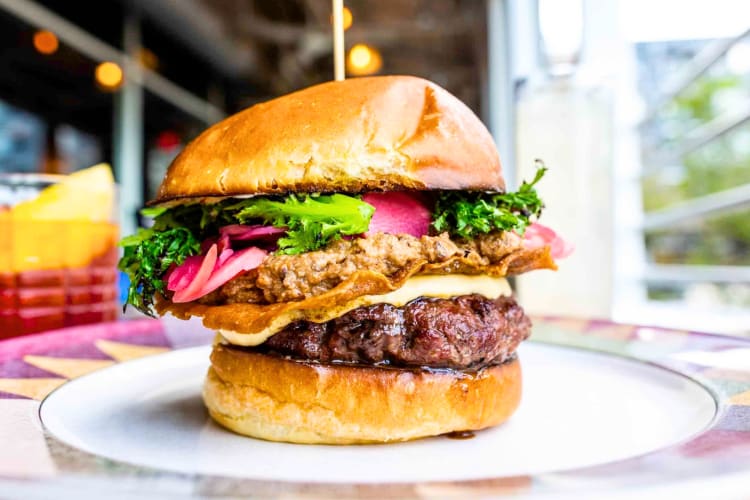 A burger with two patties, cheese and purple slaw