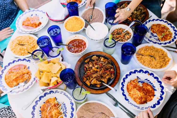 Mexican food dishes, margaritas and water in blue cups on a table