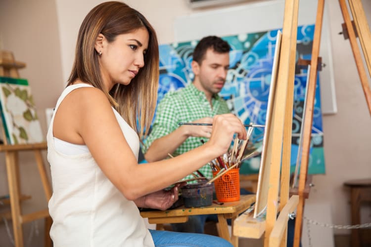 Two people painting on canvases