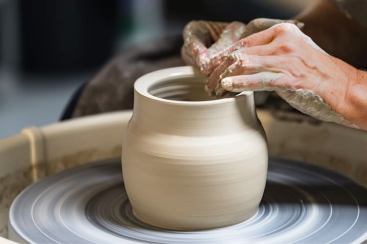 A person crafting clay on a pottery wheel