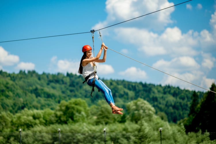 A woman ziplining above a green forest