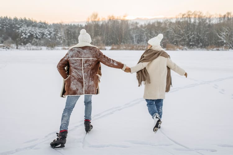 A couple ice skating on an outdoor rink at sunset