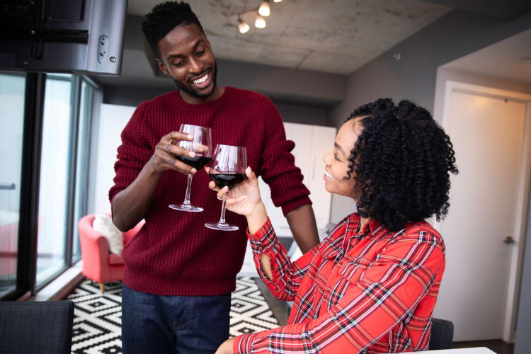 A couple cheersing wine glasses in an apartment