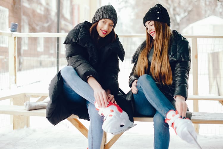 Two women putting ice skates on