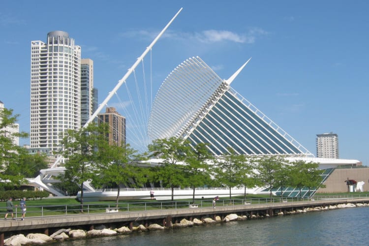 A modern building next to green trees and a river