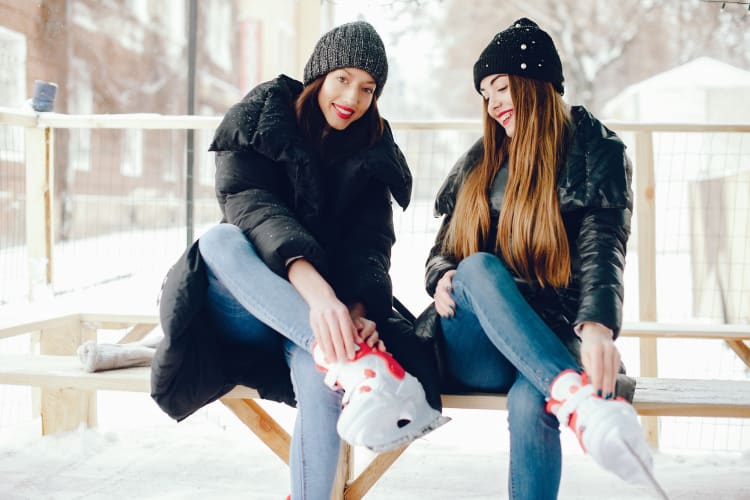 Two women putting ice skates on