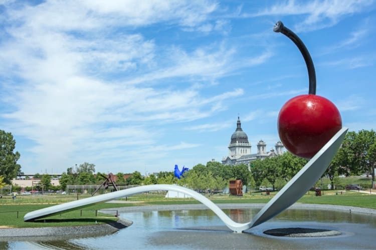 A sculpture of a cherry on a spoon in a park