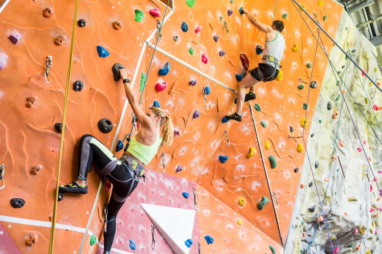 Two people rock climbing on an indoor wall