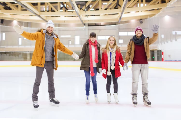 Four people skating at an indoor ice rink