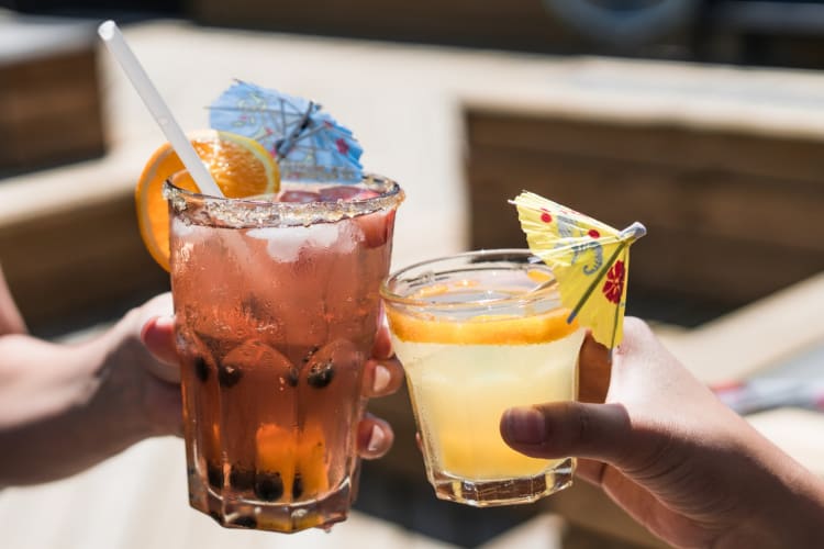 Two people cheersing fruit drinks with cocktail umbrellas