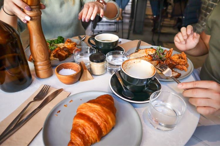 Two people eating at a breakfast table with breakfast dishes and coffee