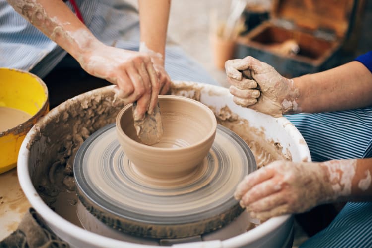 People making pottery on a pottery wheel