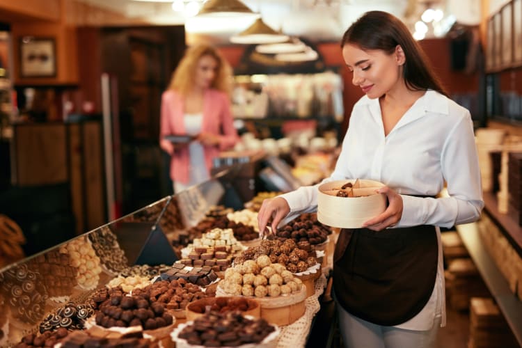 A woman putting chocolates in a box at a chocolate shop