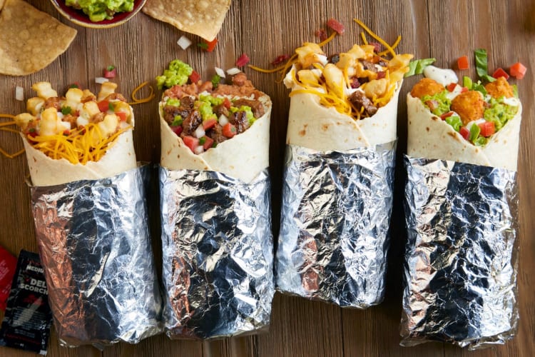 Four burritos on a wooden surface