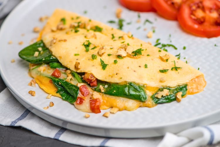 Cheese omelet with tomato slices in the background