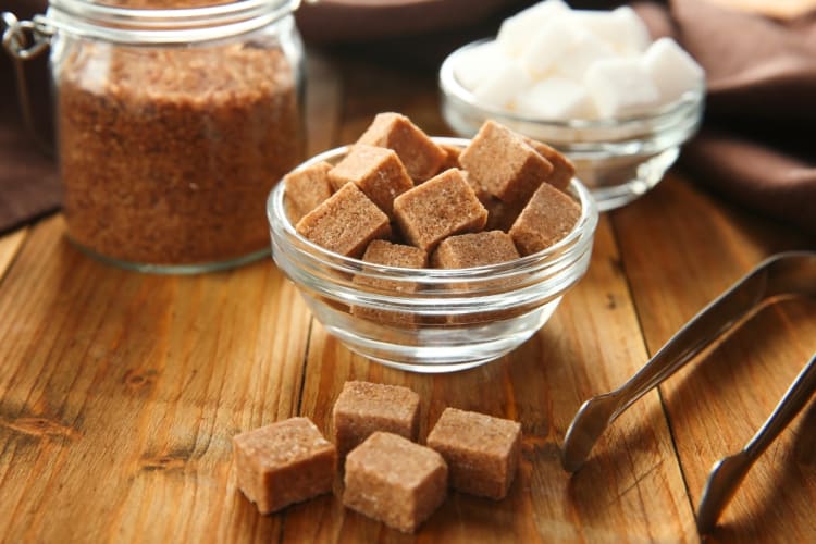 Demerara sugar cubes next to jars of sugar