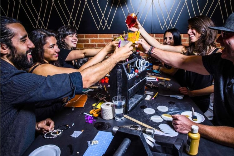 A group of people at a table with drinks and craft supplies