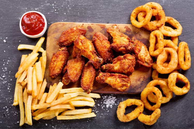 Chicken wings with onion rings and fries.