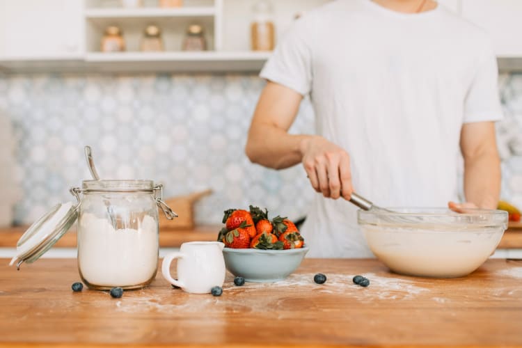 A person making pancakes on a counter with ingredients