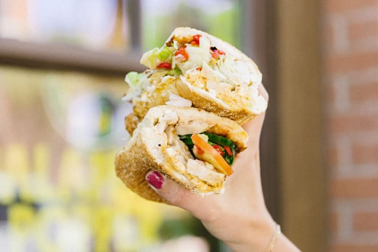 Person's hand holding two sandwich halves from Potbelly