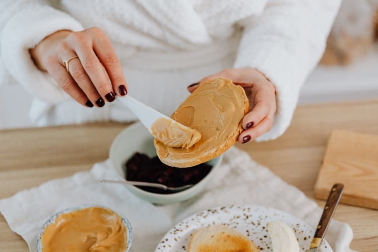 A person putting peanut butter on bread