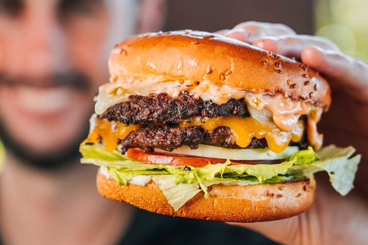 Hand holding the Monster burger from Dog House Grill