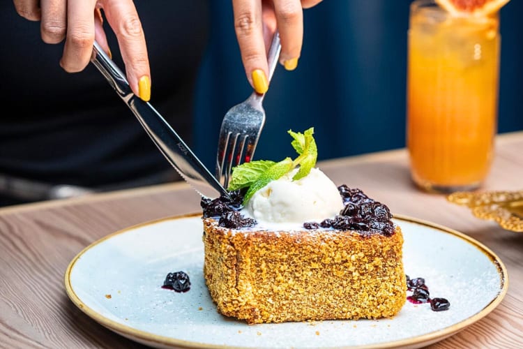 Person's hands cutting a slice from the Captain Crunch French toast, from Dolly Varden