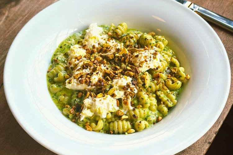 A bowl of pasta with green sauce