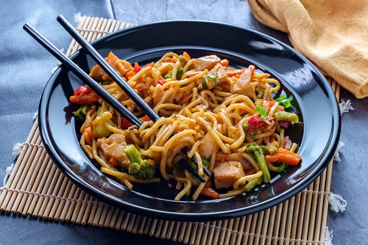 Chinese chicken chow mein in a bowl with chopsticks