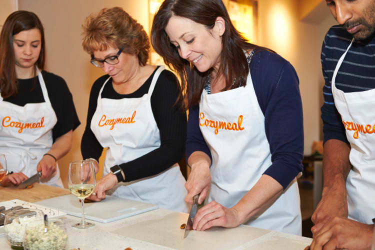 Four people chopping food while taking a Cozymeal cooking class