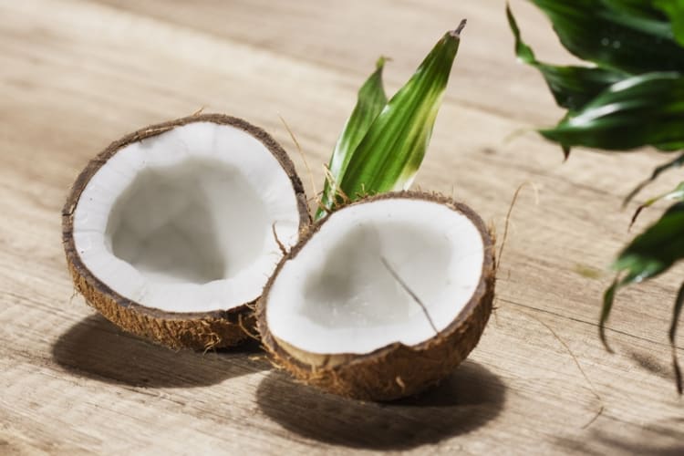 Two halves of a coconut on a wooden table.