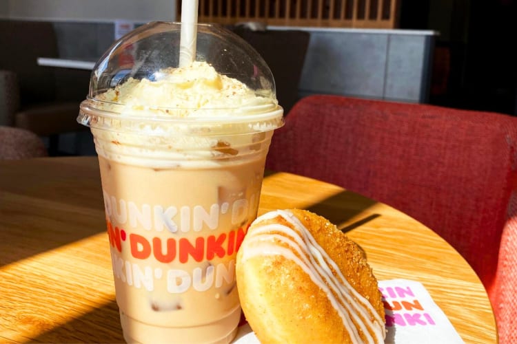 A Dunkin' Donuts drink and donut on a table.