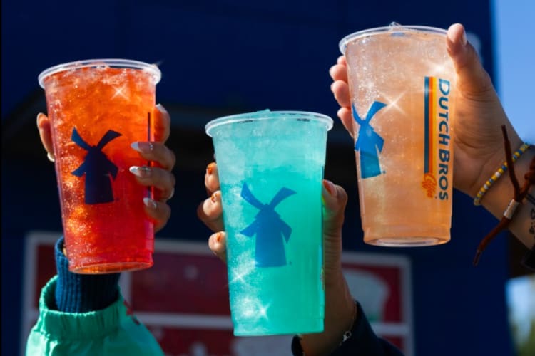 Three people holding colorful drinks in clear takeout cups